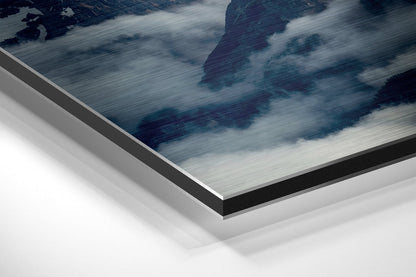 Close-up angled view of brushed aluminium Dibond panel showing layered edge construction with mountain landscape artwork featuring blue tones and white clouds.