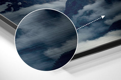 Close-up detail shot of brushed aluminum surface with directional arrow and layered mountain landscape in blue and white tones.