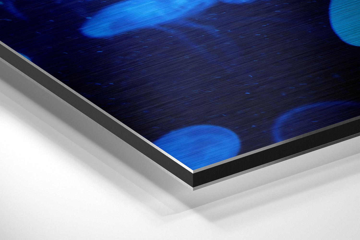 Close-up angled view of brushed aluminum dibond panel edge, showing layered construction with blue jellyfish artwork visible on top surface.