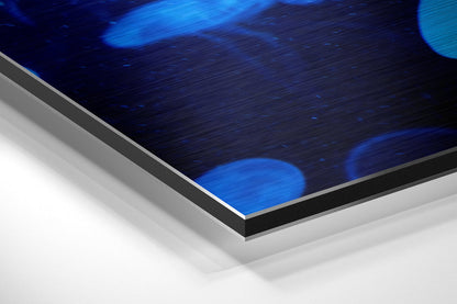 Close-up angled view of brushed aluminum dibond panel edge, showing layered construction with blue jellyfish artwork visible on top surface.