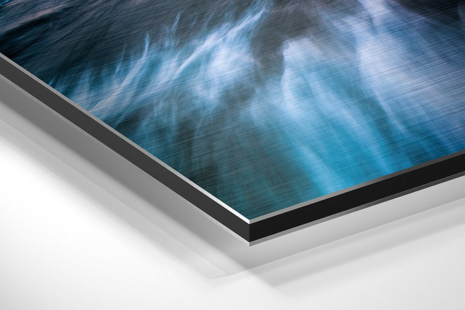 Angled close-up of brushed aluminium Dibond wall art displaying blue ocean and sky with white clouds, showing layered edge construction.