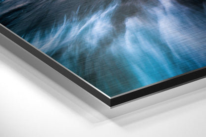 Angled close-up of brushed aluminium Dibond wall art displaying blue ocean and sky with white clouds, showing layered edge construction.