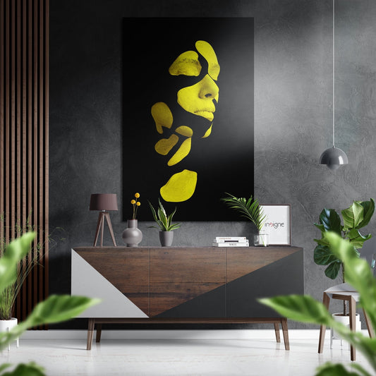 Yellow fragmented woman's face wall art displayed above a wooden console table in a modern interior setting with plants and pendant lighting.