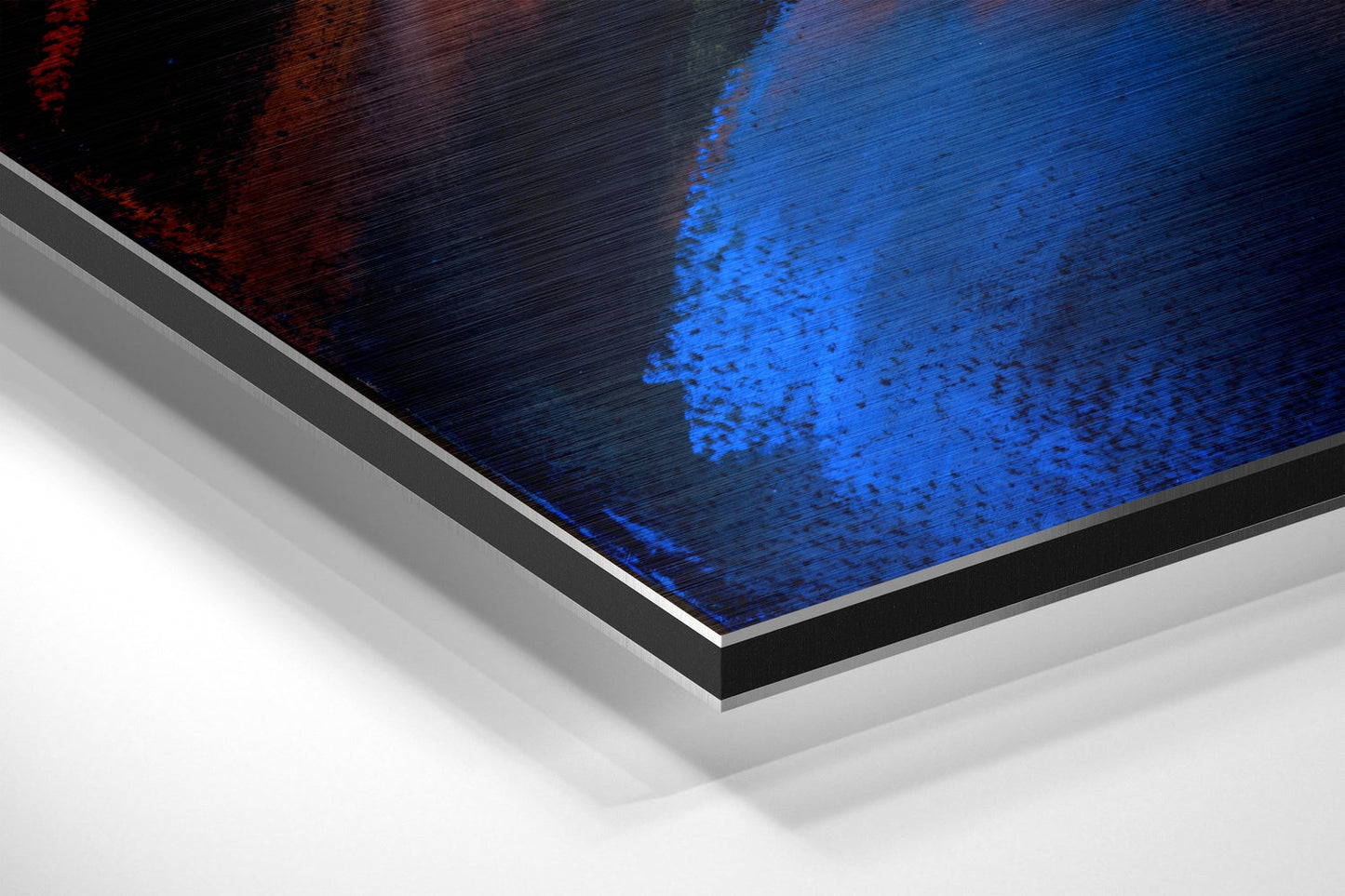 Close-up angled view of brushed aluminum dibond print edge showing blue and red tones with layered mounting construction.