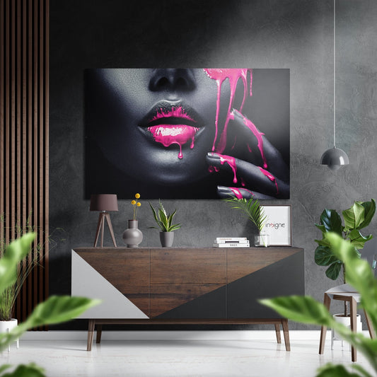 Modern interior with black and gray wall displaying pink and black portrait art above wooden console table with decor.