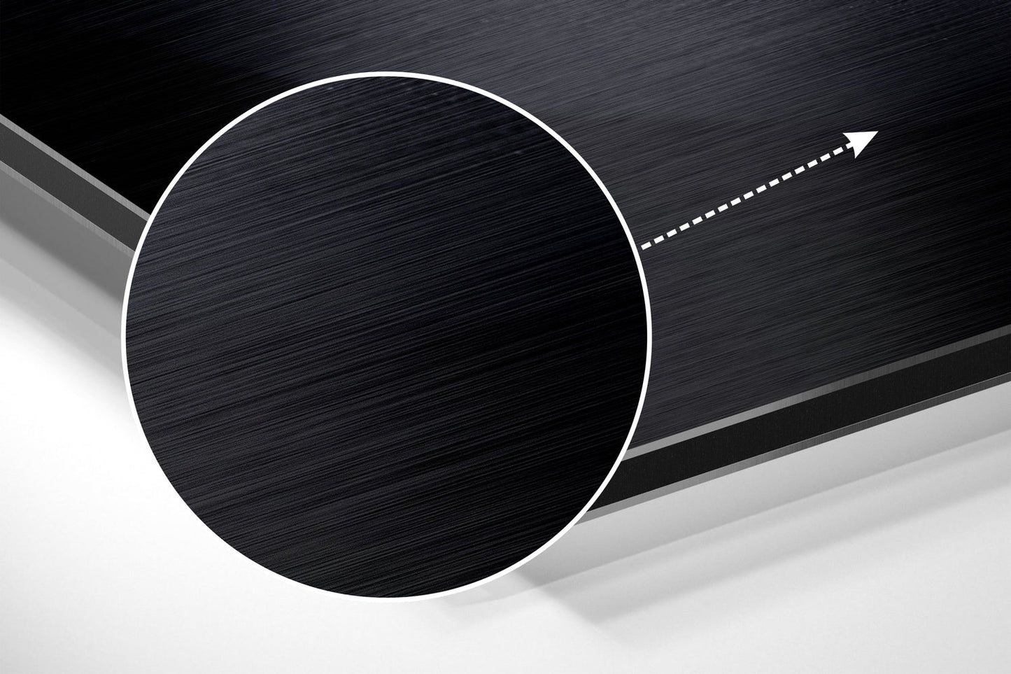 Close-up angled view of brushed black aluminum circular panel with white border and directional arrow on textured dark background.
