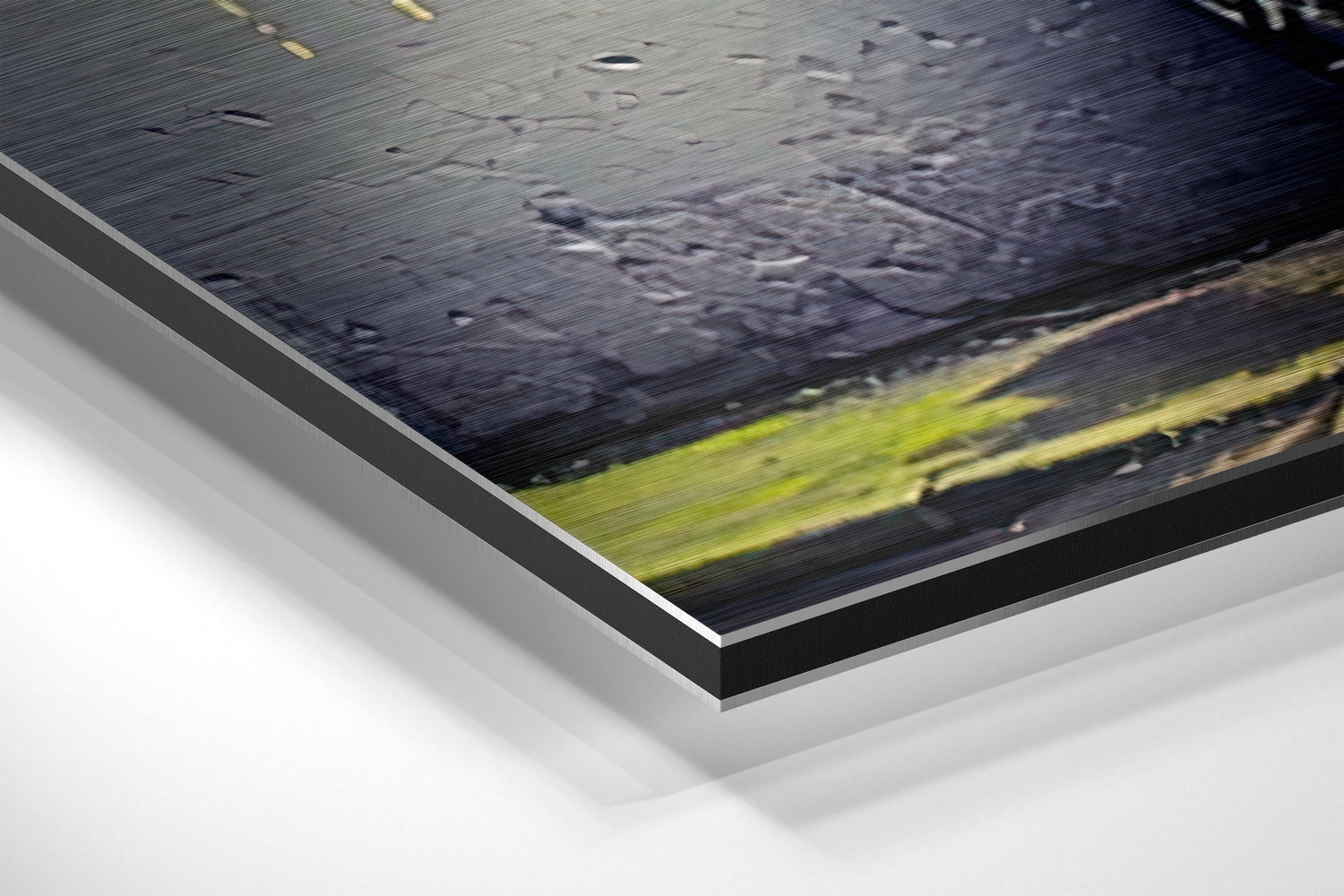 Close-up angled view of brushed aluminum Dibond print showing layered edge construction with dark landscape featuring yellow-green horizontal stripe.