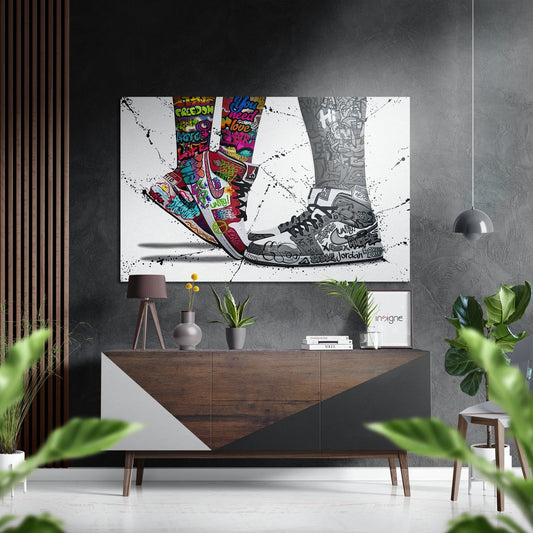 Graffiti sneakers wall art displayed above a wooden dresser in a modern living room with plants and pendant lighting.