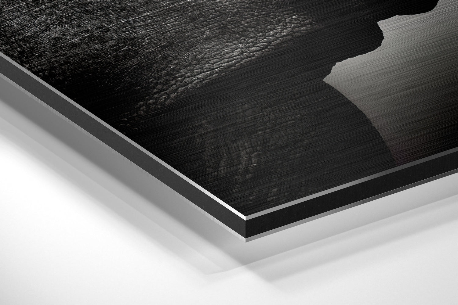 Close-up angled view of layered Dibond wall art showing brushed black aluminum surface with white backing layers against white background.