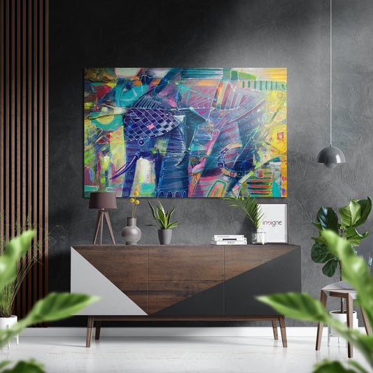 Colorful abstract elephant brushed aluminum wall art displayed above a wooden dresser in a modern interior setting with plants and pendant lighting.
