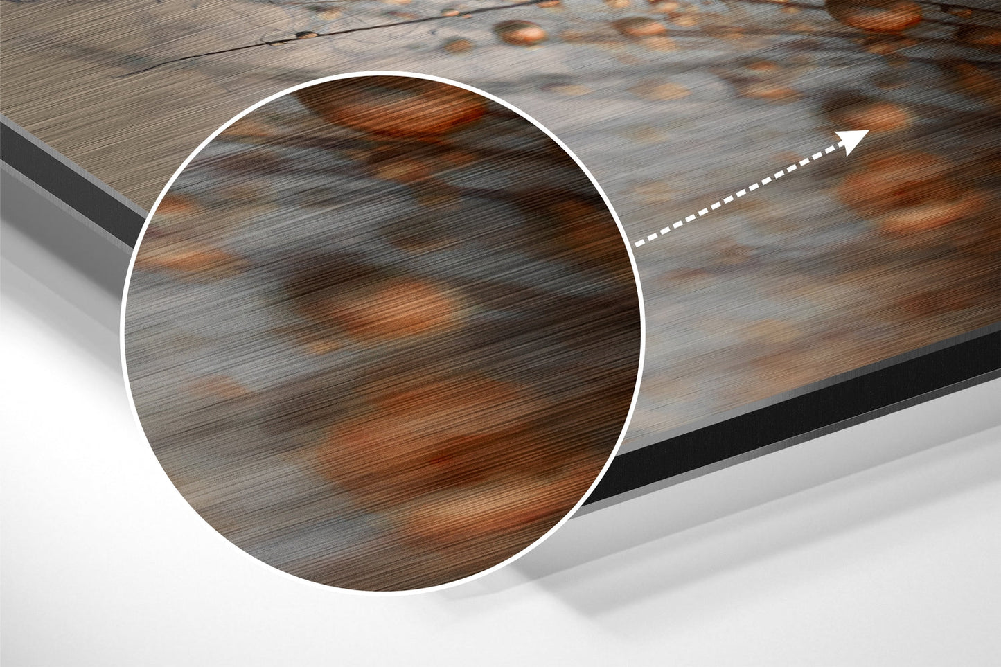 Close-up circular detail showing brushed aluminum surface with brown and gray wood grain texture pattern and directional arrow.