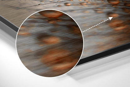 Close-up circular detail showing brushed aluminum surface with brown and gray wood grain texture pattern and directional arrow.
