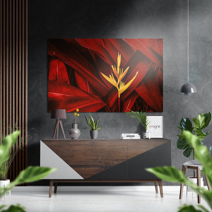 Red and yellow tropical flower metal wall art displayed above a wood and white dresser in a modern gray interior with plants and pendant lamp.