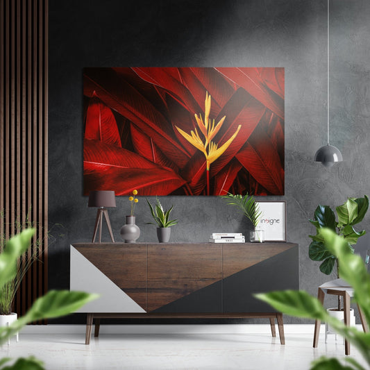 Red and yellow tropical flower metal wall art displayed above a wood and white dresser in a modern gray interior with plants and pendant lamp.