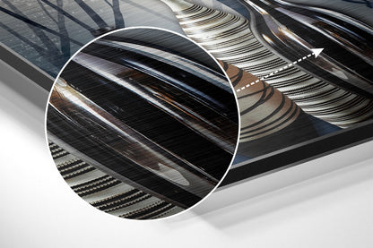 Close-up detail of brushed aluminium wall art showing layered metallic surfaces with diagonal striations and brown-toned accents in angled perspective.