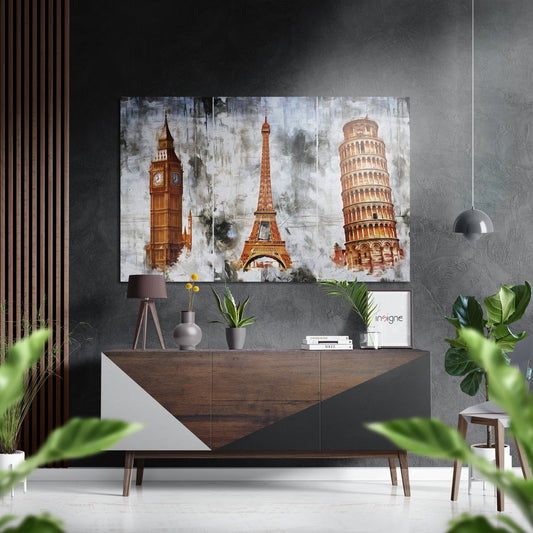 Three-panel brushed aluminium wall art featuring Big Ben, Eiffel Tower, and Leaning Tower of Pisa in warm tones displayed above a wooden console in modern interior.