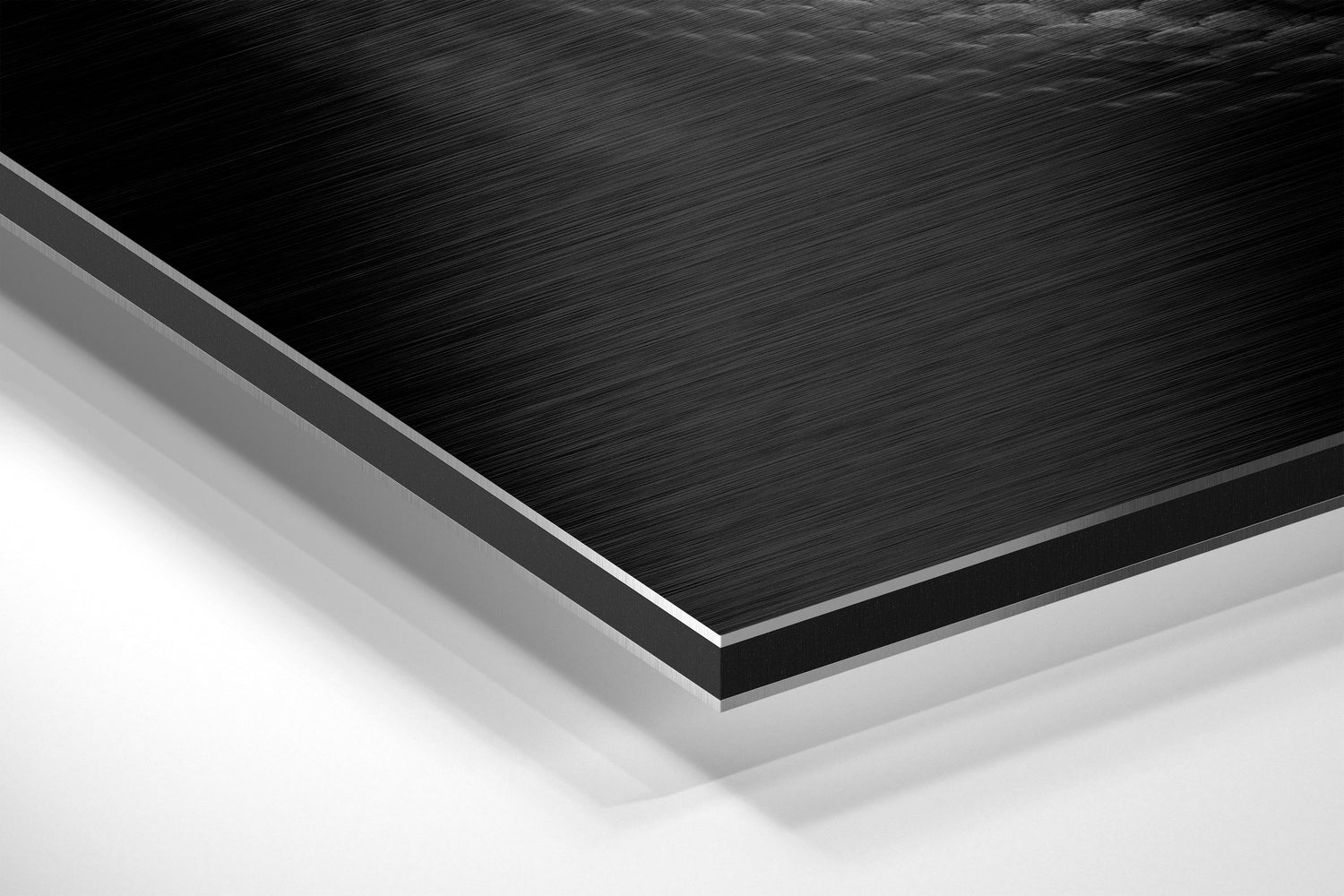 Close-up angled view of layered Dibond panel showing brushed black aluminum surface with gray and white backing layers.