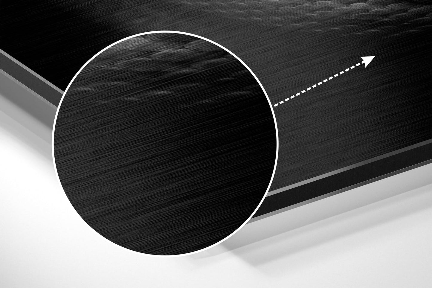 Close-up angled view of brushed aluminum wall art showing circular black disk with white outline and directional arrow detail on textured gray background.