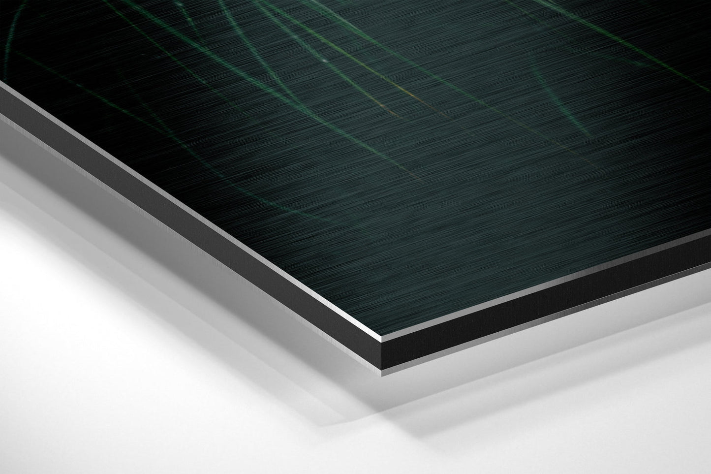 Close-up angled view of layered brushed aluminum Dibond panel showing teal and dark green textured surface with silver edge trim and white backing.