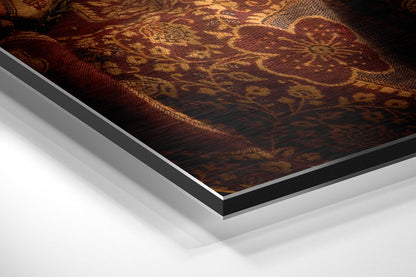 Close-up angled view of layered Dibond panel edges showing dark frame and white backing against rich burgundy and gold patterned fabric surface.