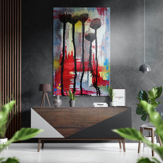 Abstract brushstroke artwork in red, yellow, and blue with silhouetted flower stems displayed above wooden console table in modern interior.