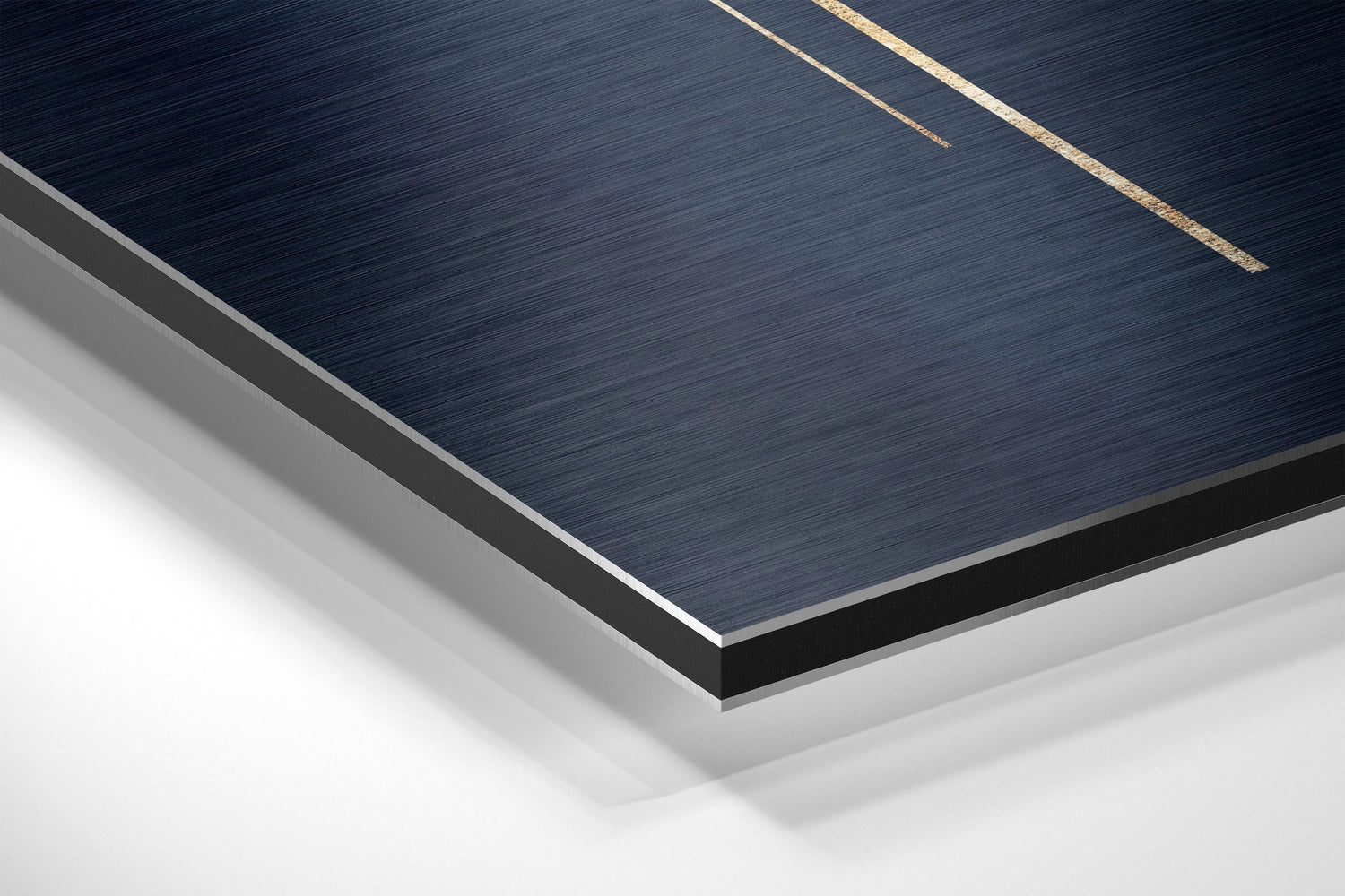 Close-up angled view of layered Dibond wall art showing dark brushed aluminum surface with gold accent lines and white backing layers.