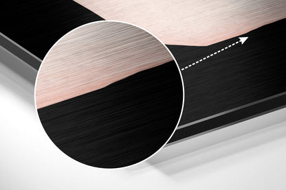 Close-up angled view of circular brushed aluminum wall art with horizontal black and rose gold striped pattern and white border.
