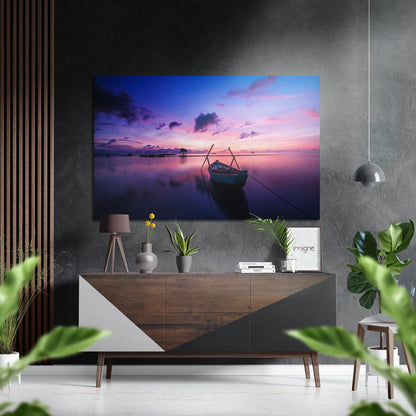 Brushed aluminium dibond wall art displaying a purple and pink sunset over calm water with a moored boat, hung above a wooden console table in a modern interior.