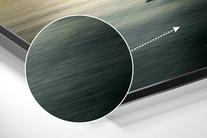 Close-up angled view of brushed aluminium Dibond wall art showing circular green textured disc with white border and directional arrow.