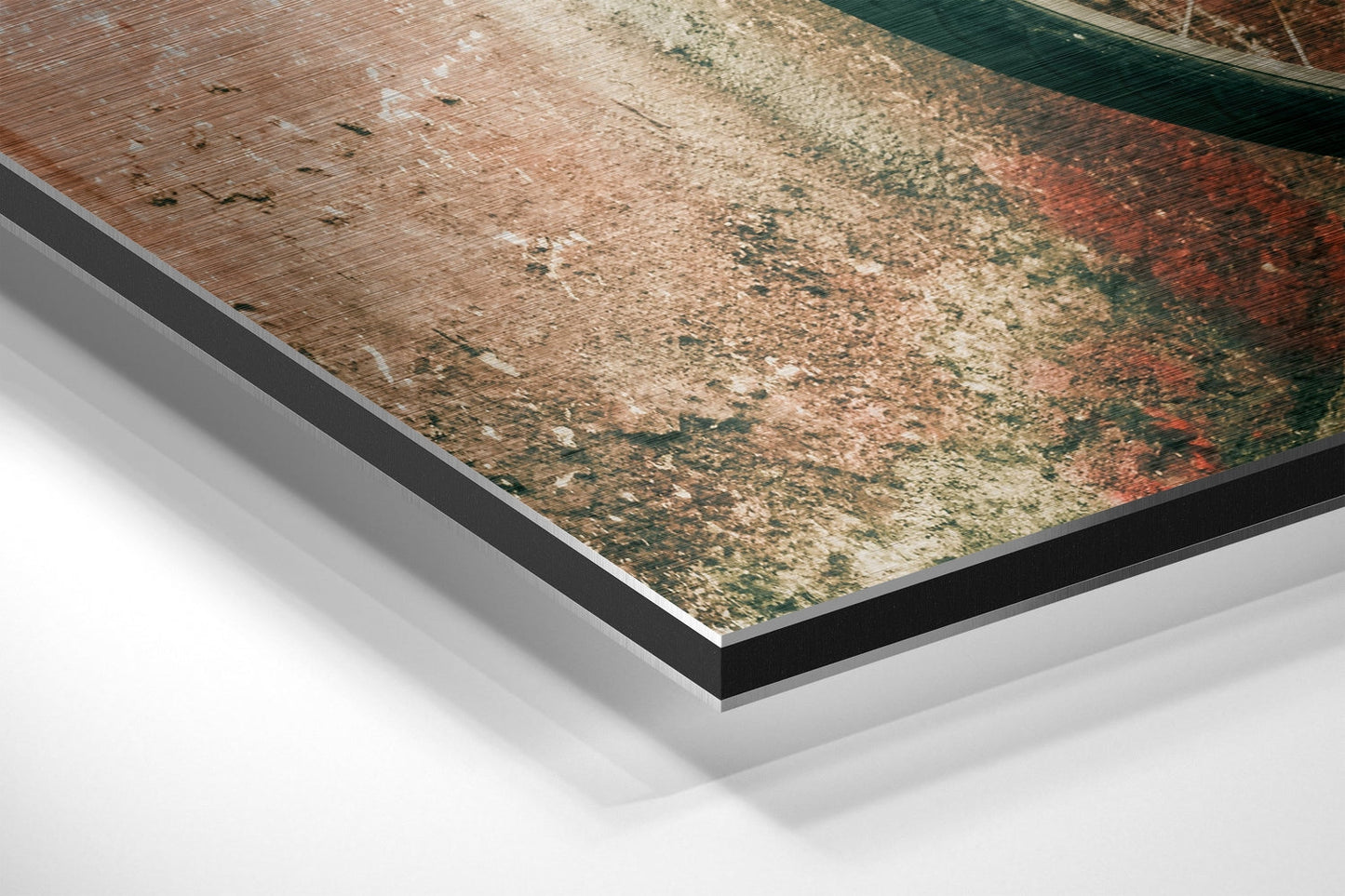 Close-up angled view of layered Dibond wall art showing black and white composite backing beneath weathered rustic surface with brown, green, and red tones.