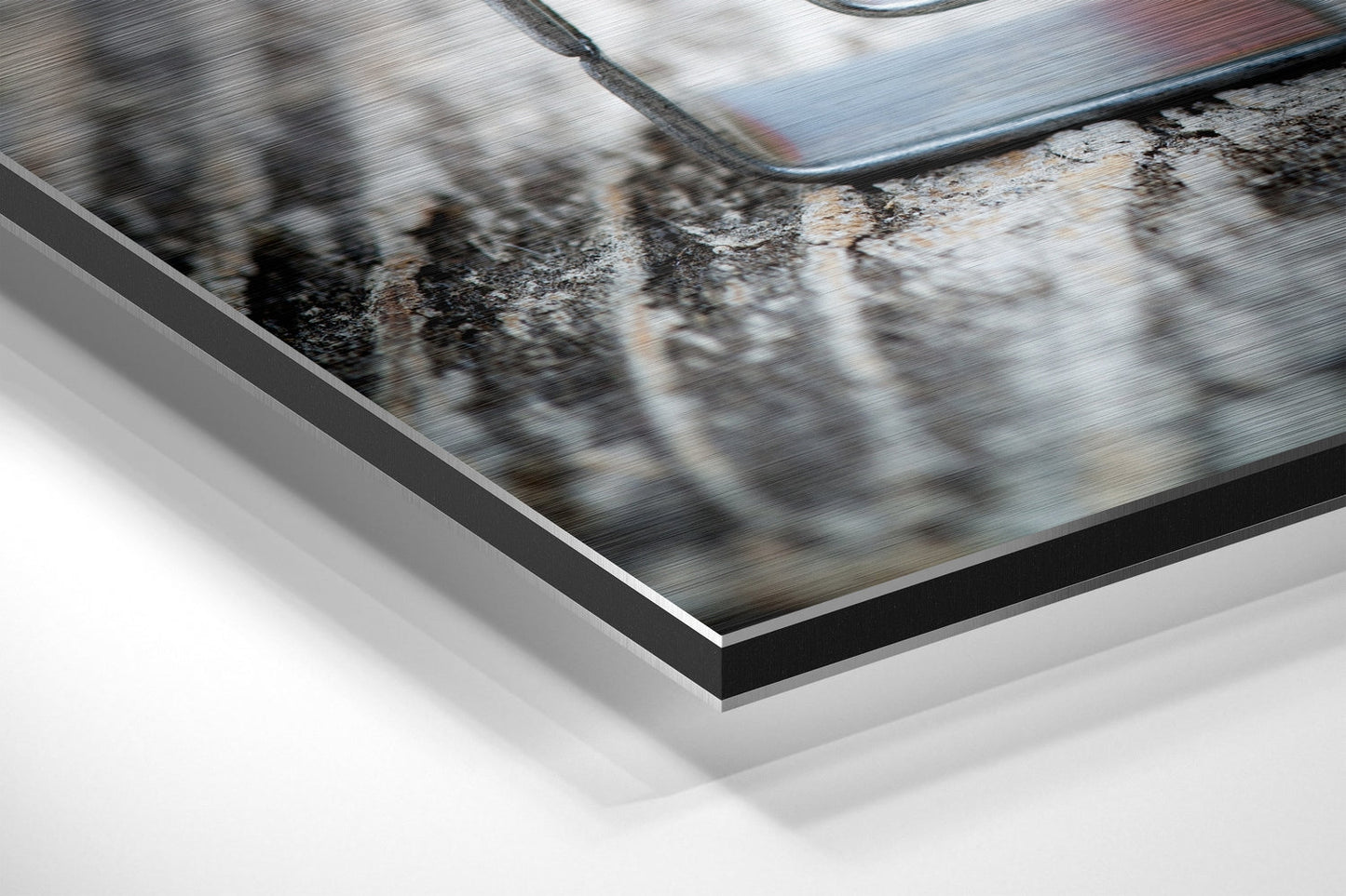 Close-up angled view of brushed aluminium Dibond print showing layered edge detail with black border frame and white backing.