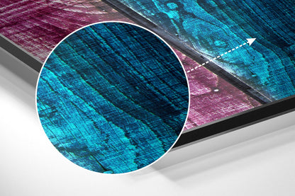 Close-up angled view of brushed aluminum wall art with cyan and magenta geometric patterns and diagonal striations.