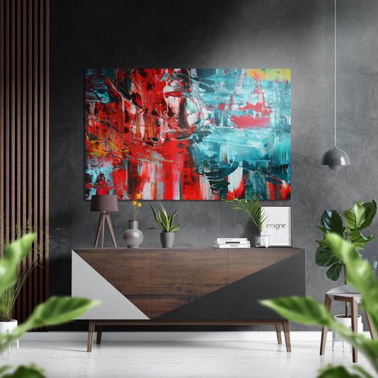 Abstract red and turquoise brushed aluminum wall art displayed above a wooden console table in a modern interior setting.