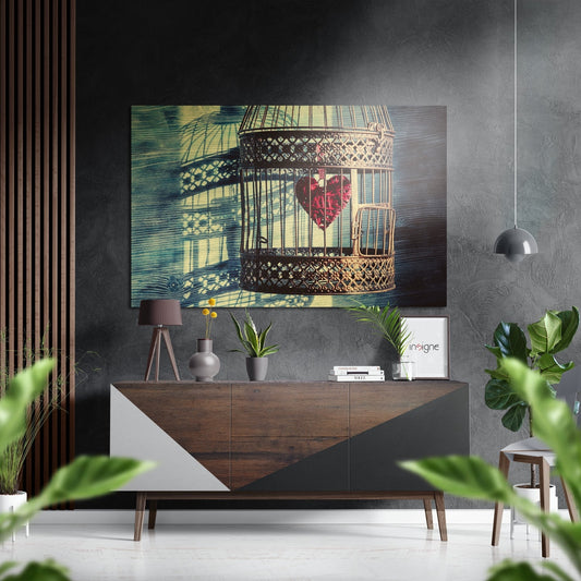 Brushed aluminum wall art featuring ornate birdcage with red flower and shadow patterns displayed above wooden dresser in modern interior setting.