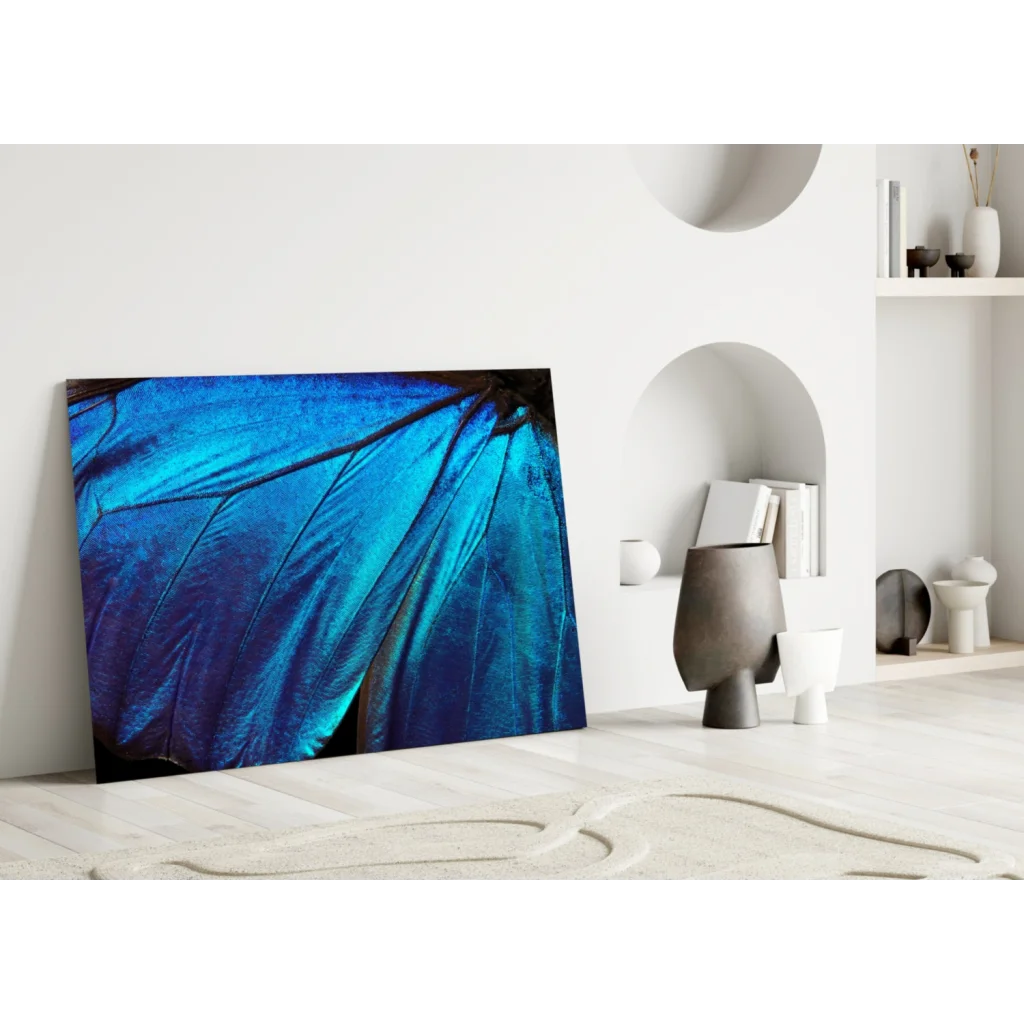 Vibrant blue butterfly wing glass wall art print leaning against white wall
