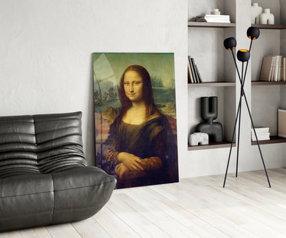 Mona Lisa glass wall art leaning against white wall in modern living room with black leather chair and shelving unit.