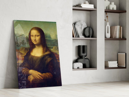 Mona Lisa glass wall art leaning against white wall beside white shelving unit with decorative objects and books.
