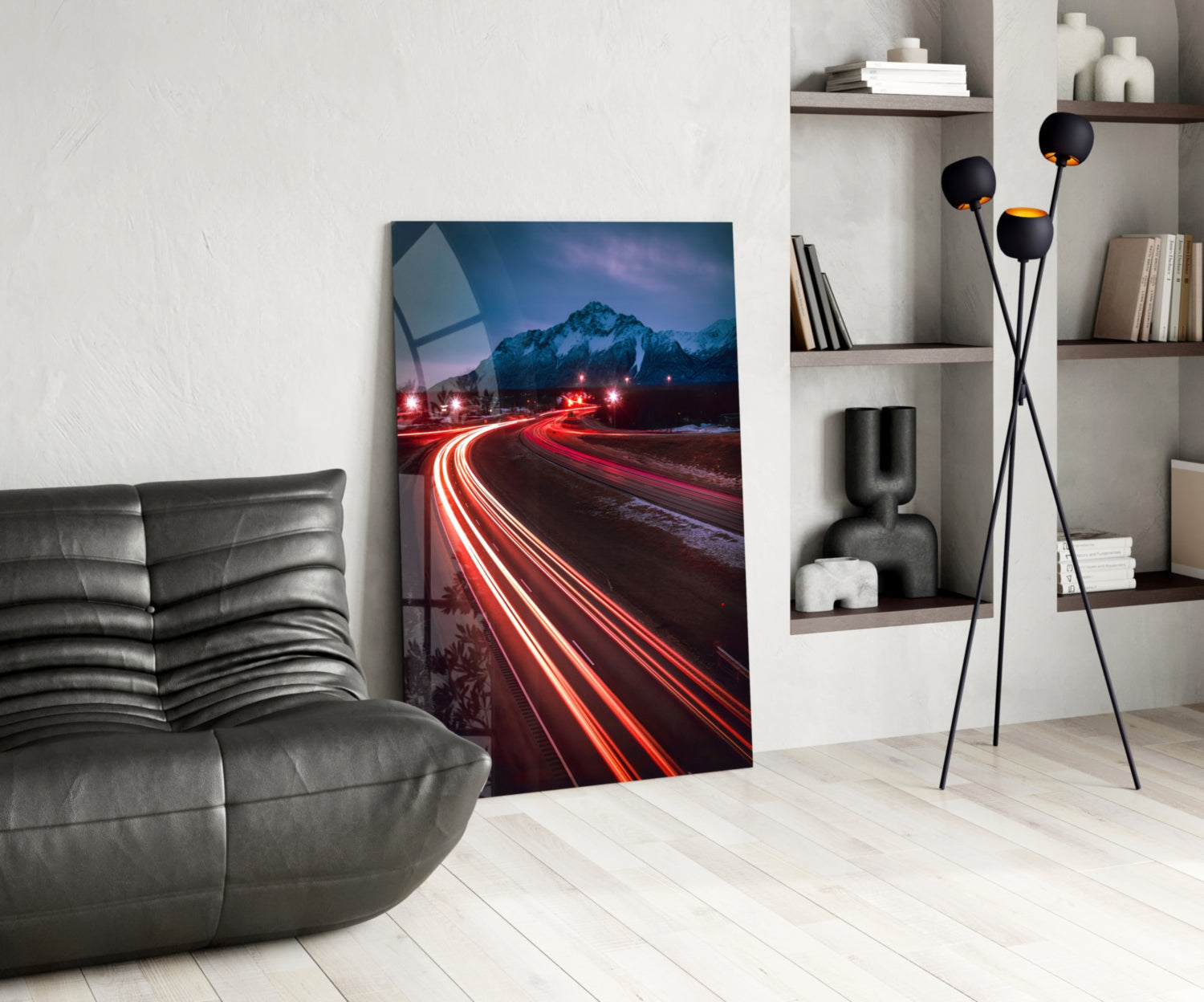 Road Glass Wall Art displayed in modern living room with gray leather chair, black floor lamp, and white shelving unit.
