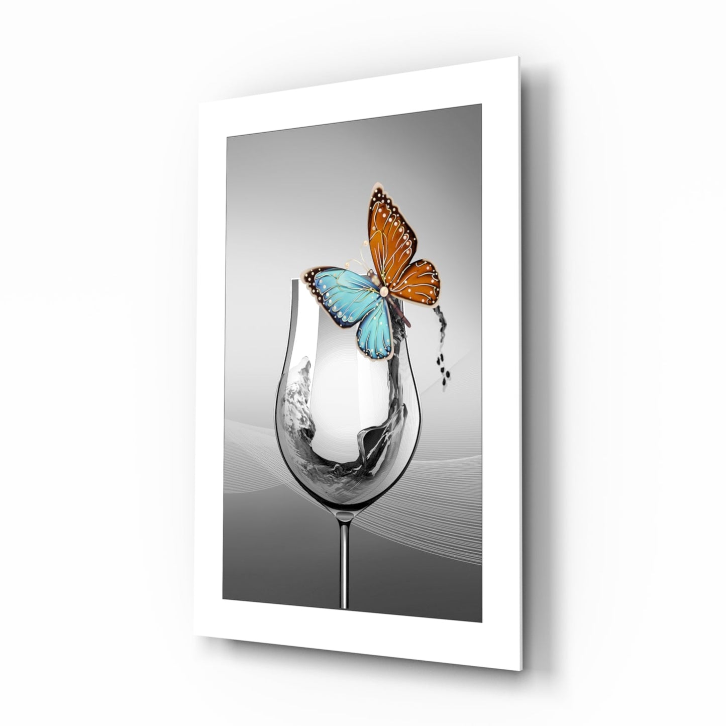 White-framed wall art displaying a tilted wine glass with colorful butterflies perched on its rim against a gray background.