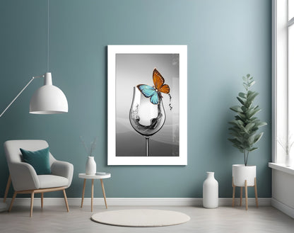 Framed white-matted art print featuring water splashing from a goblet with orange and blue butterflies, displayed on teal wall.