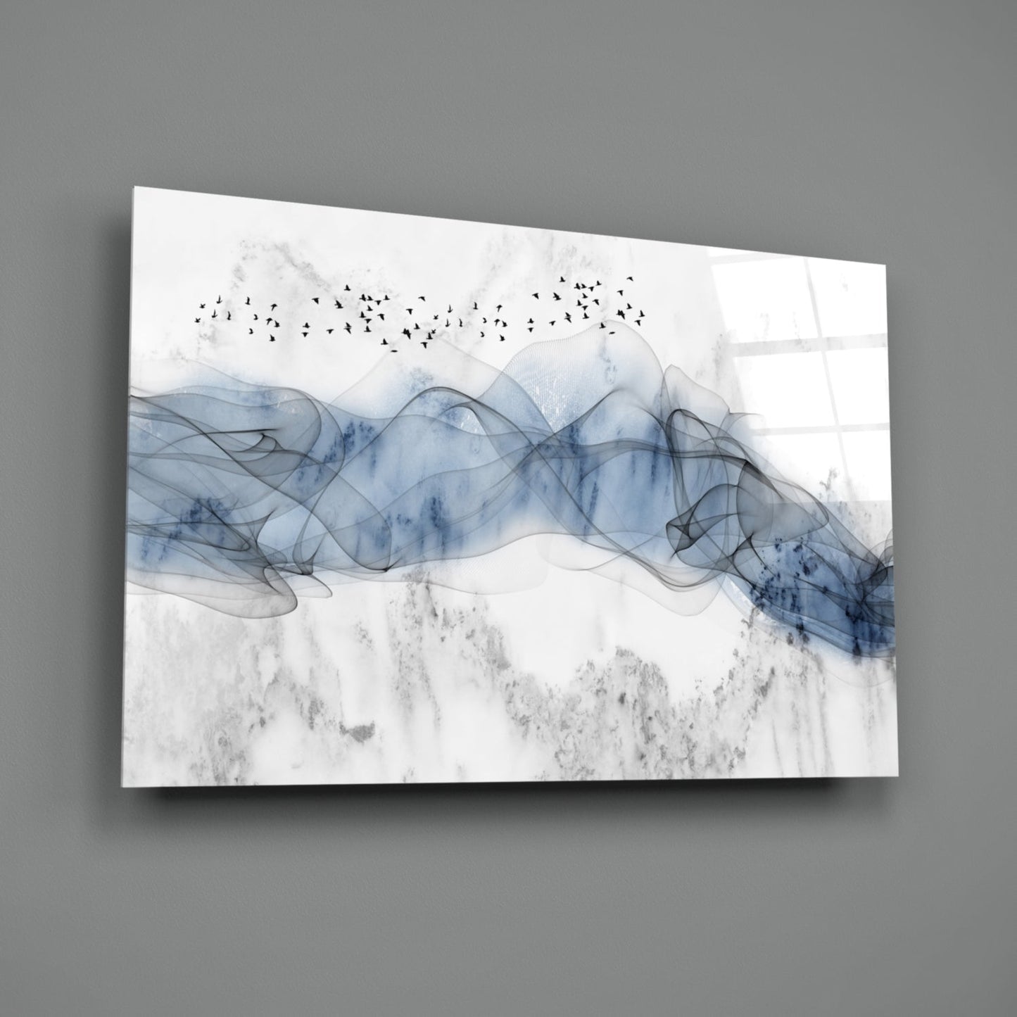 Blue Fog Glass Wall Art displayed at an angle against gray wall, showing blue watercolor waves with flock of birds in white sky.