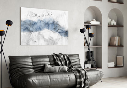 Blue Fog glass wall art with abstract blue and gray flowing patterns and birds displayed above black leather sofa in modern living room setting.