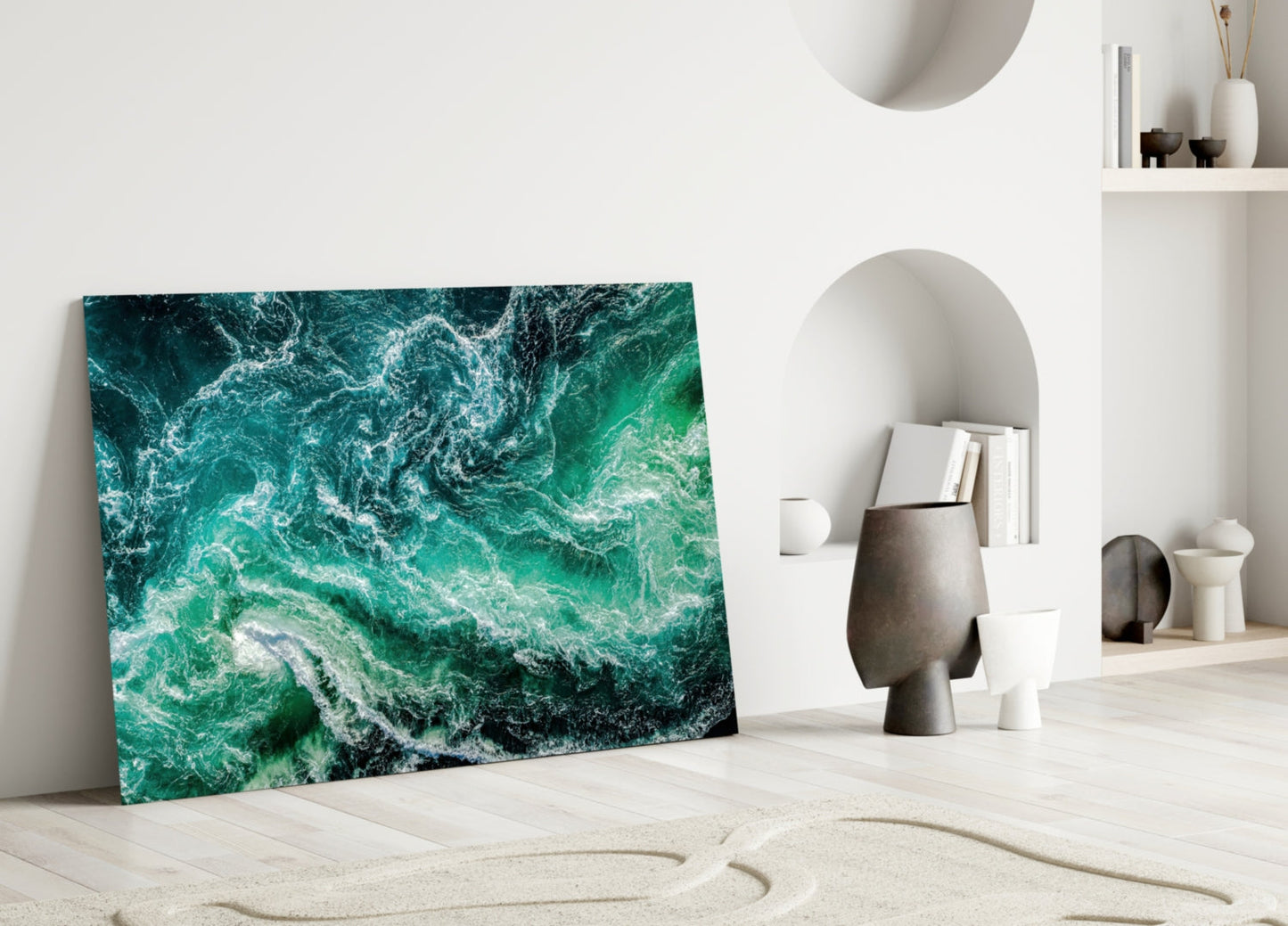 Green Waves Glass Wall Art leaning against white wall in minimalist interior with sand, shelving, and decorative objects.