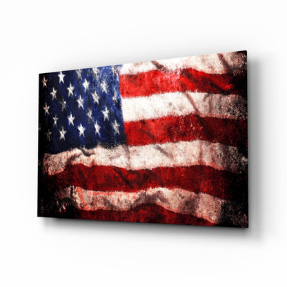 Angled three-quarter view of a distressed American flag glass wall art panel with red, white, and blue colors against a white background.