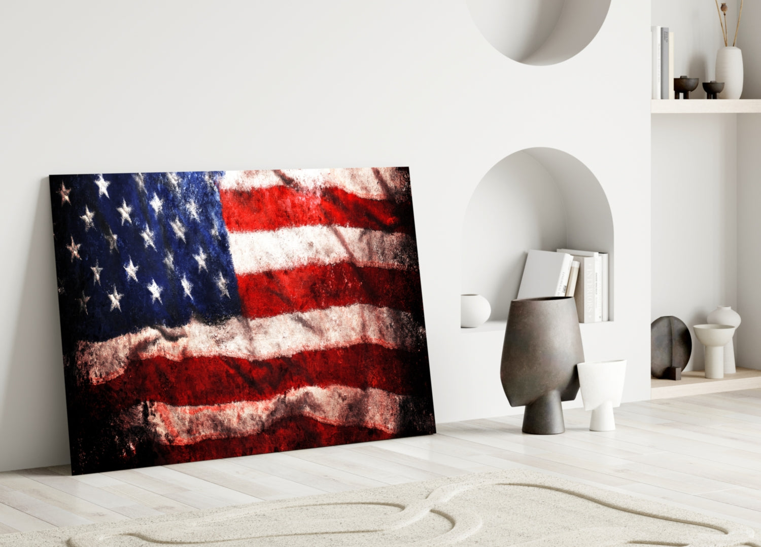 Textured American flag glass art leaning against white wall in minimalist room setting with decorative objects.