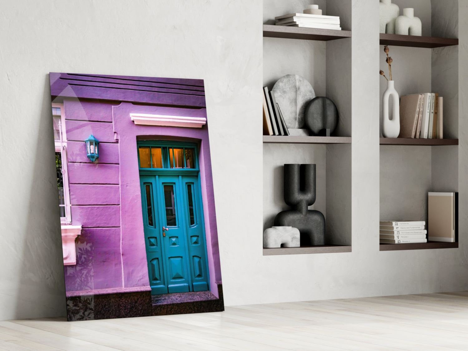 Purple House Glass Wall Art leaning against white wall next to shelving with books and decorative objects.
