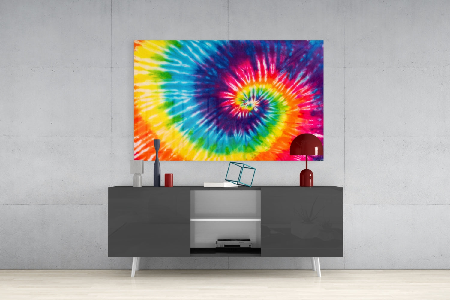 Vibrant tie-dye spiral glass wall art displayed above a dark media console in a modern living room setting.