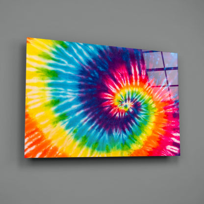 Rainbow tie-dye spiral mosaic glass wall art mounted on gray wall, displaying vibrant concentric color rings radiating from center.