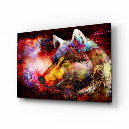 Angled view of a glass wall art panel displaying a colorful wolf's head with vibrant red, purple, blue, and yellow paint splatters against a dark background.