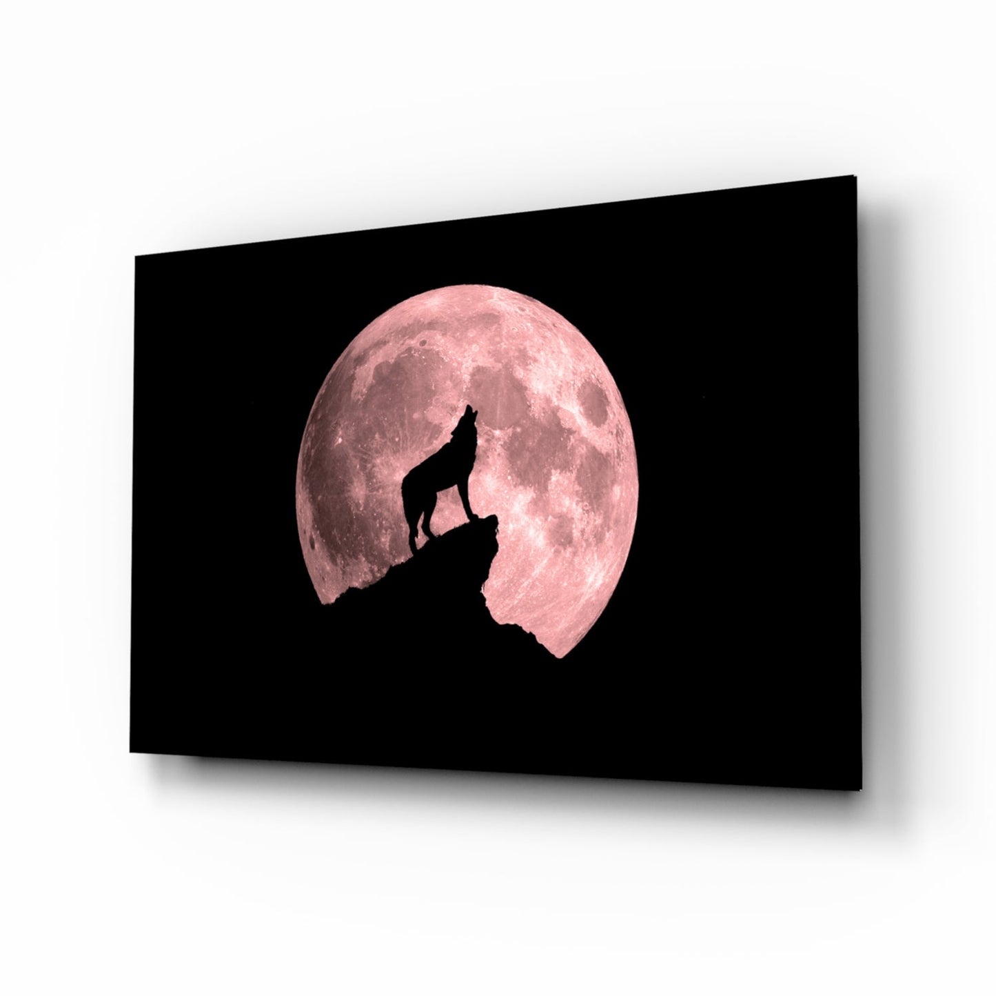 Black glass wall art panel displaying a silhouetted wolf howling on a rocky outcrop against a large pink full moon.